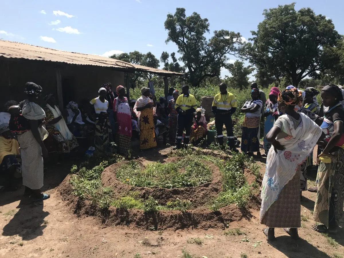 Mine staff and community members gathered around a completed spiral garden bed
